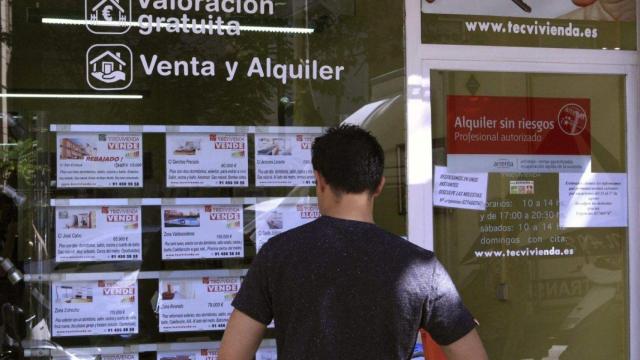 Una persona mira un escaparate de una inmobiliaria